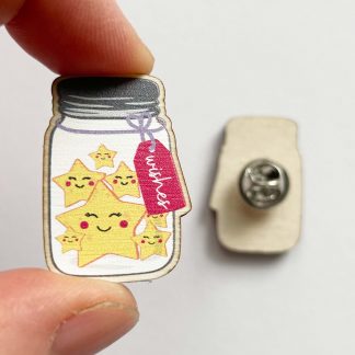 Close up of wooden 'Wishes in a Jar' pin badge held in a hand